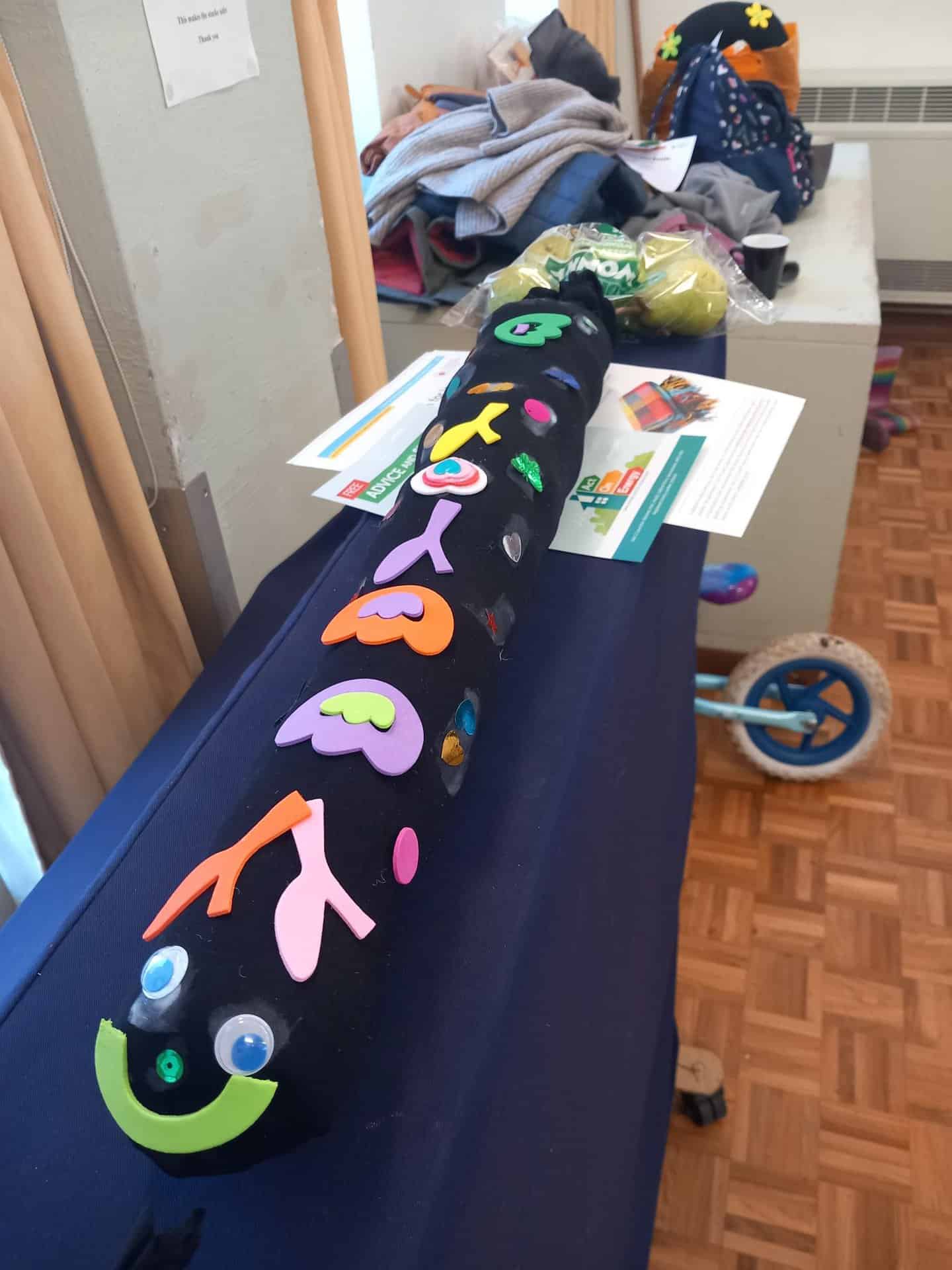 A black draught excluder with colourful foam decorations.