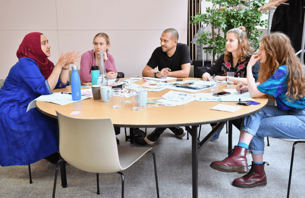 A group of young environmental activists in discussion around a table.