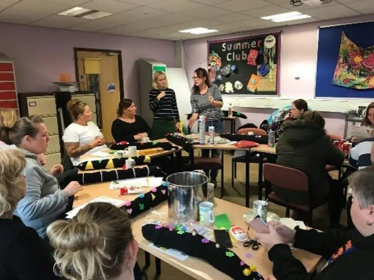 A group of people attend a community class to make a draughtproofing snake for their home