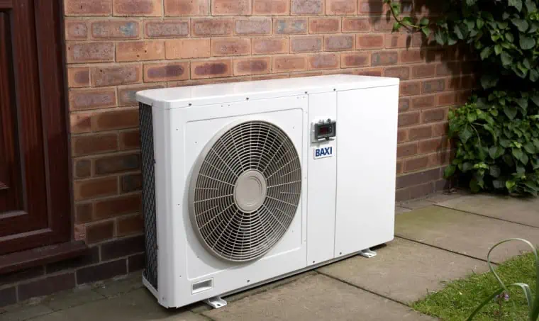 An air-source heat pump outside a bricked wall