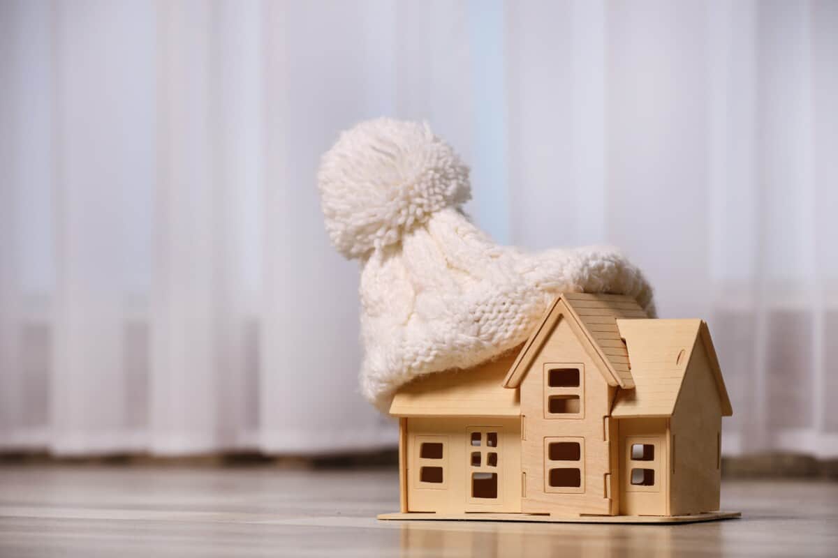 A small wooden model of a house with a beanie hat on it