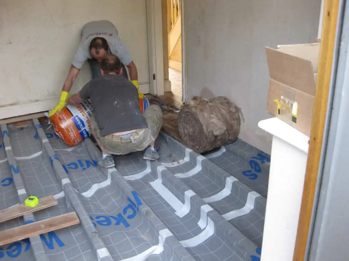 Underfloor insulation being laid between the floor joists of a Victorian home