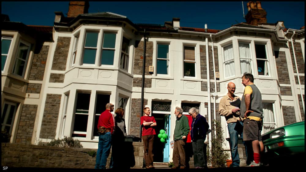 People gather outside a terraced house with bay windows for an open doors event