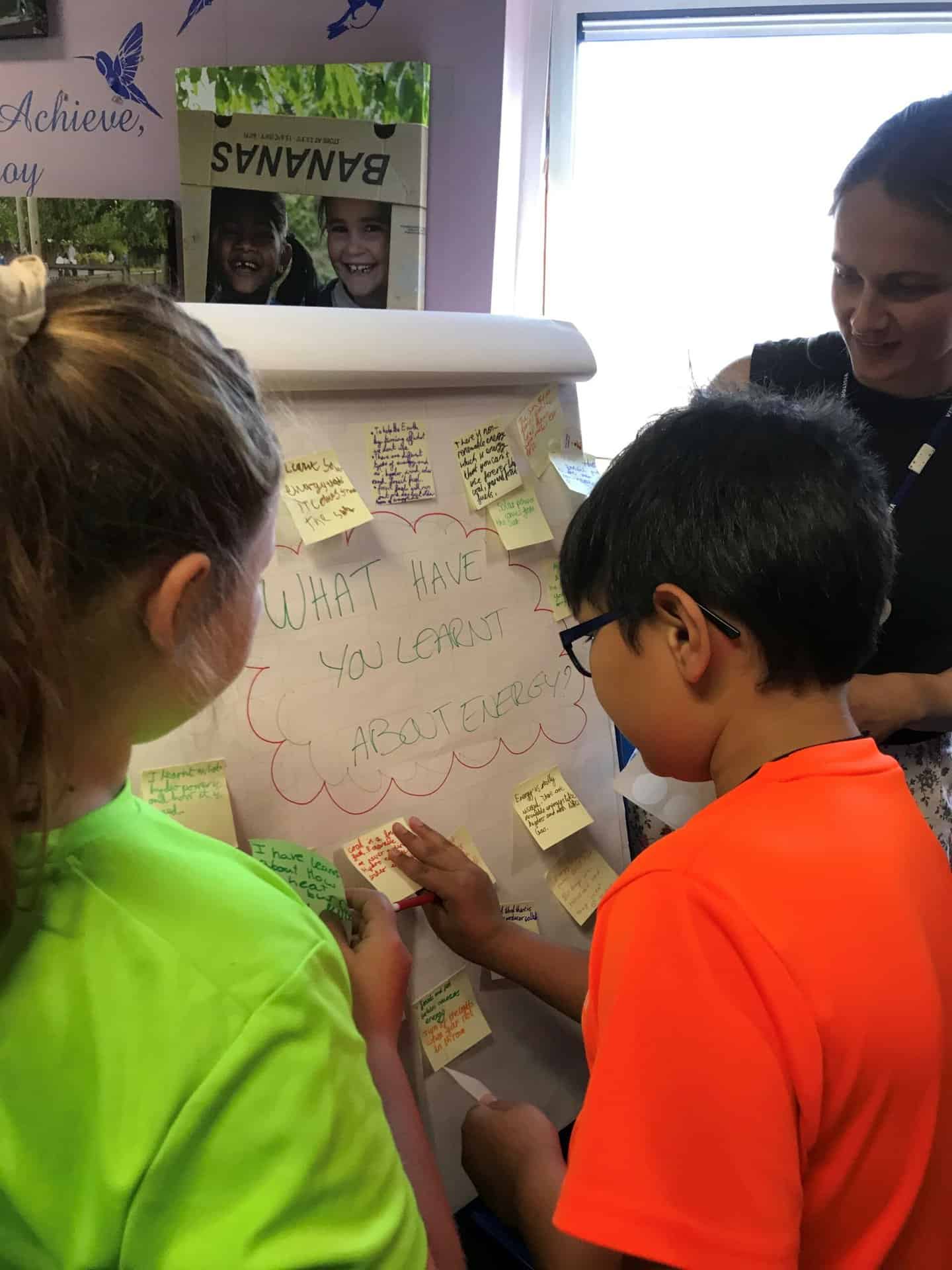 Two youn children attach post-its to a flip chart