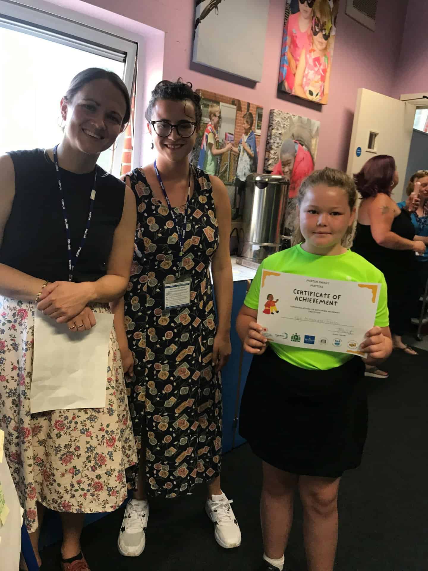 Two energy trainers from CSE stand next to a child holding their energy certificate