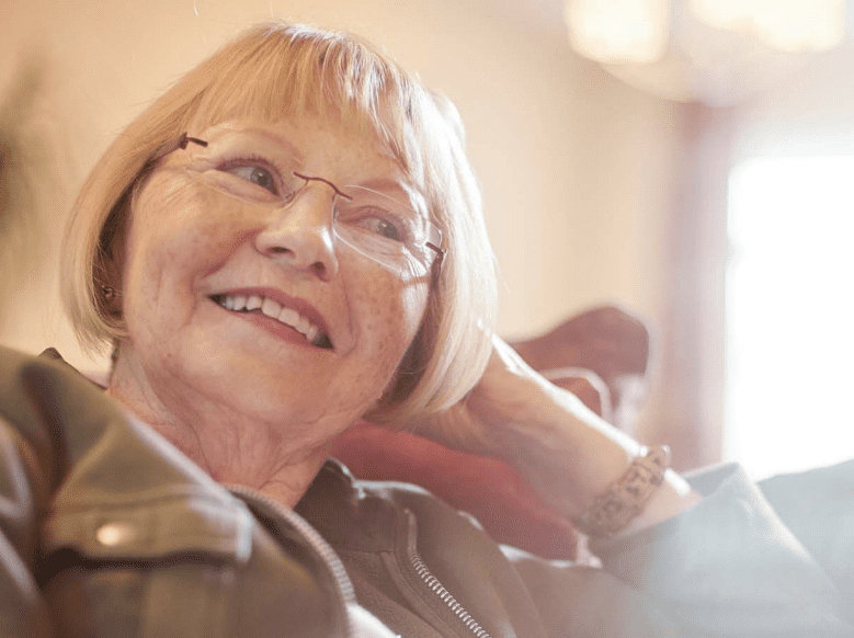 Image of a senior woman looking happy and comfortable in her home.
