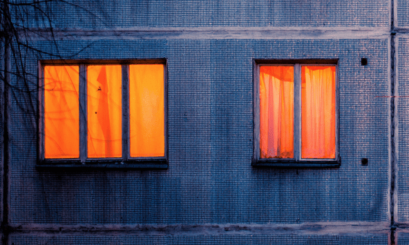 Close up of two windows of a block of flats at night.