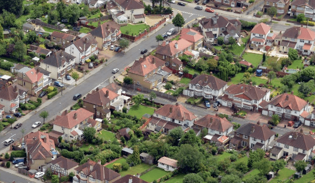 Birds-eye view of a suburb of an English town showing rooftops gardens and roads
