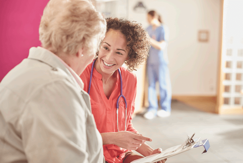 A health professional speaks to an elderly patient in hospital.