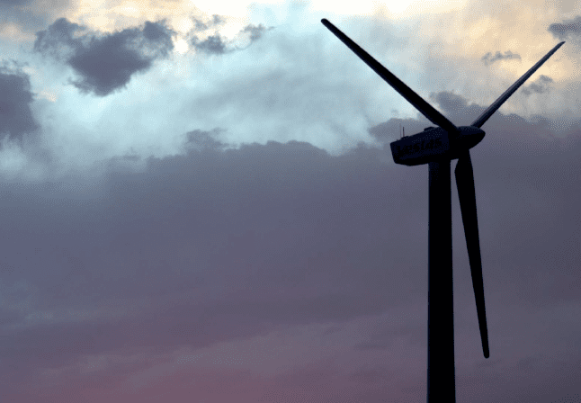 A wind turbine silhouetted against the evening sky.