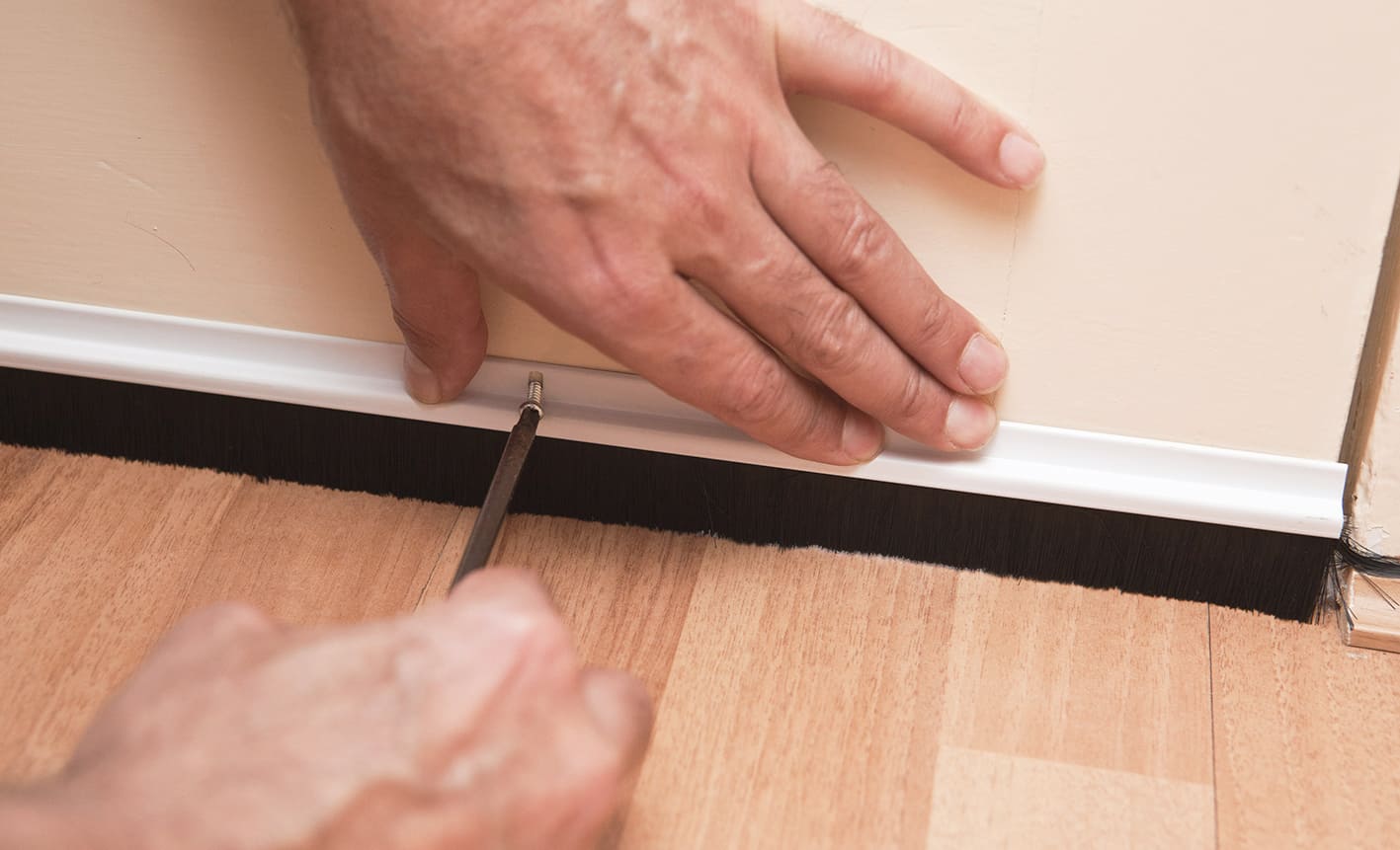 Fitting a draught-excluding brush to the foot of an interior door. 
