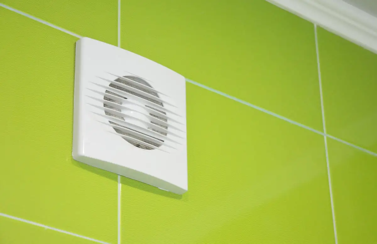 Extractor fan on green tiled bathroom wall