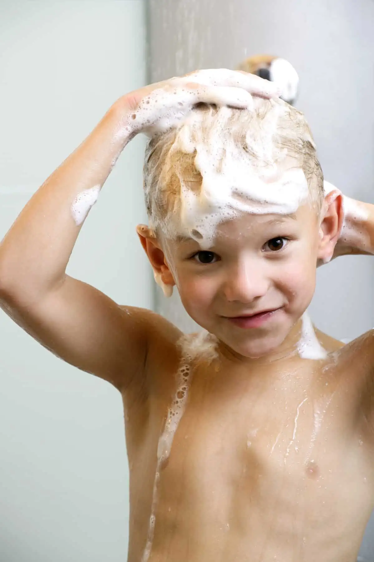 Young boy washing his head and hair in the shower
