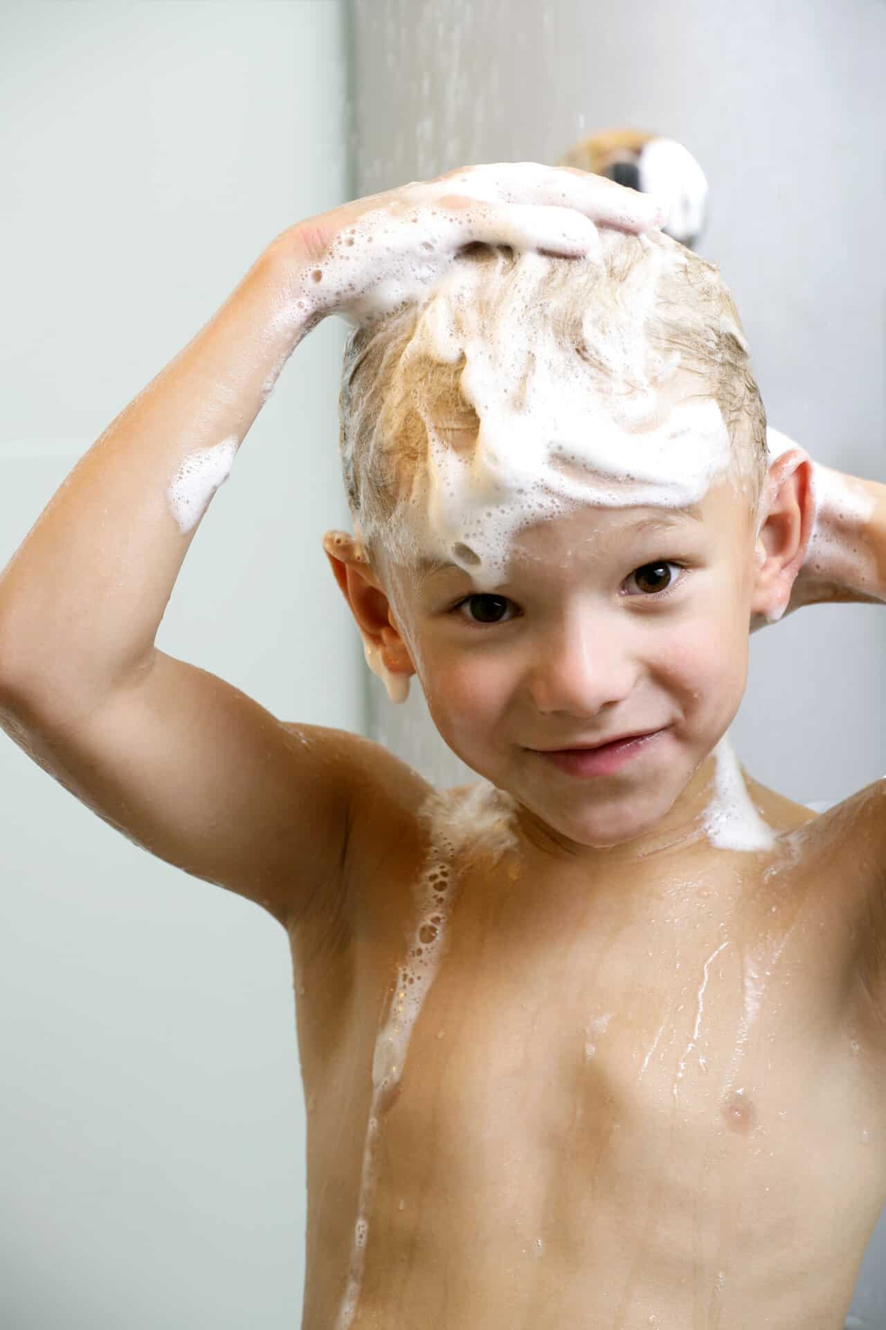 Young boy washing his head and hair in the shower