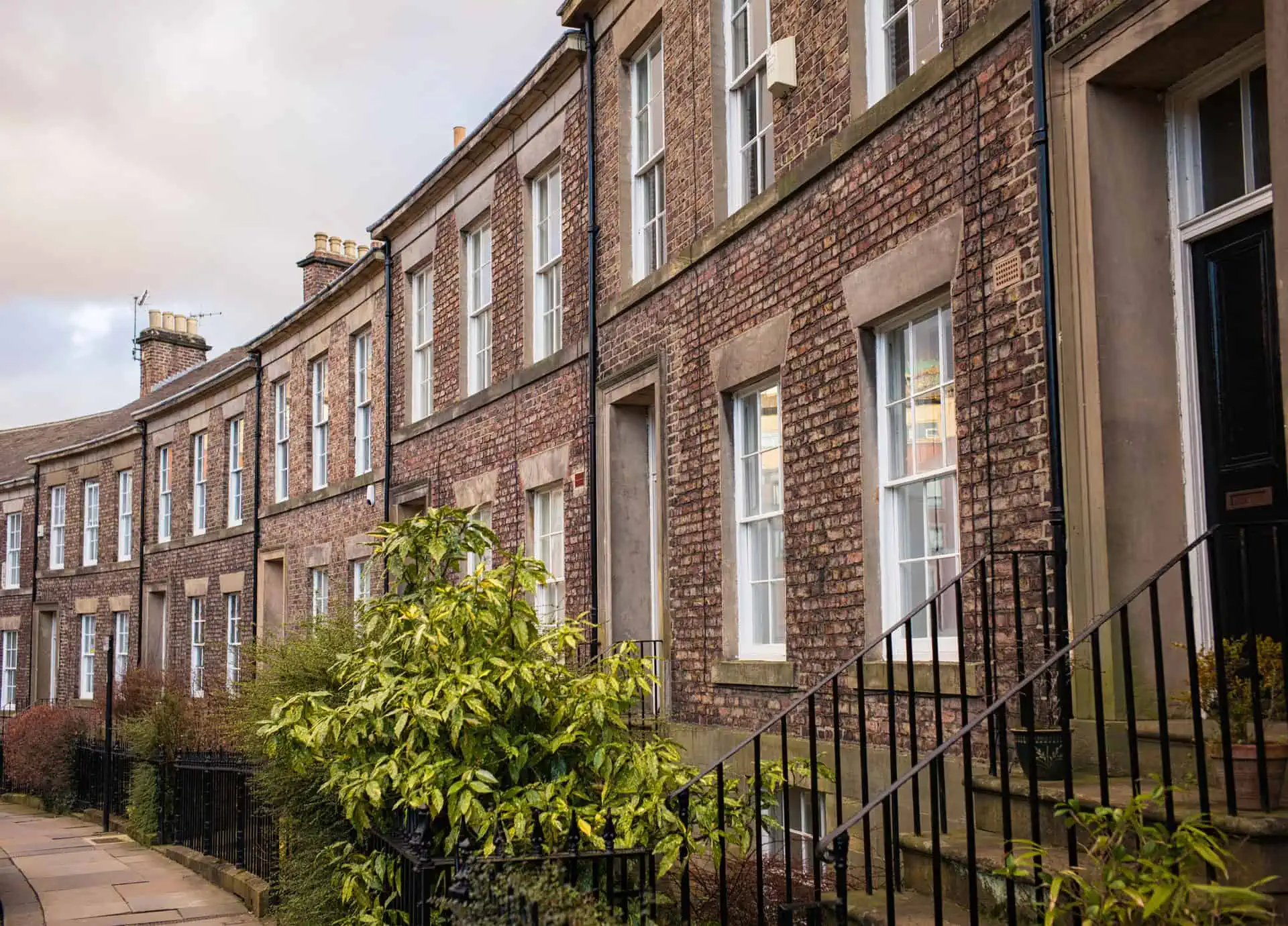 A curving row of traditional brick-built terraced townhouse properties in Newcastle, England.