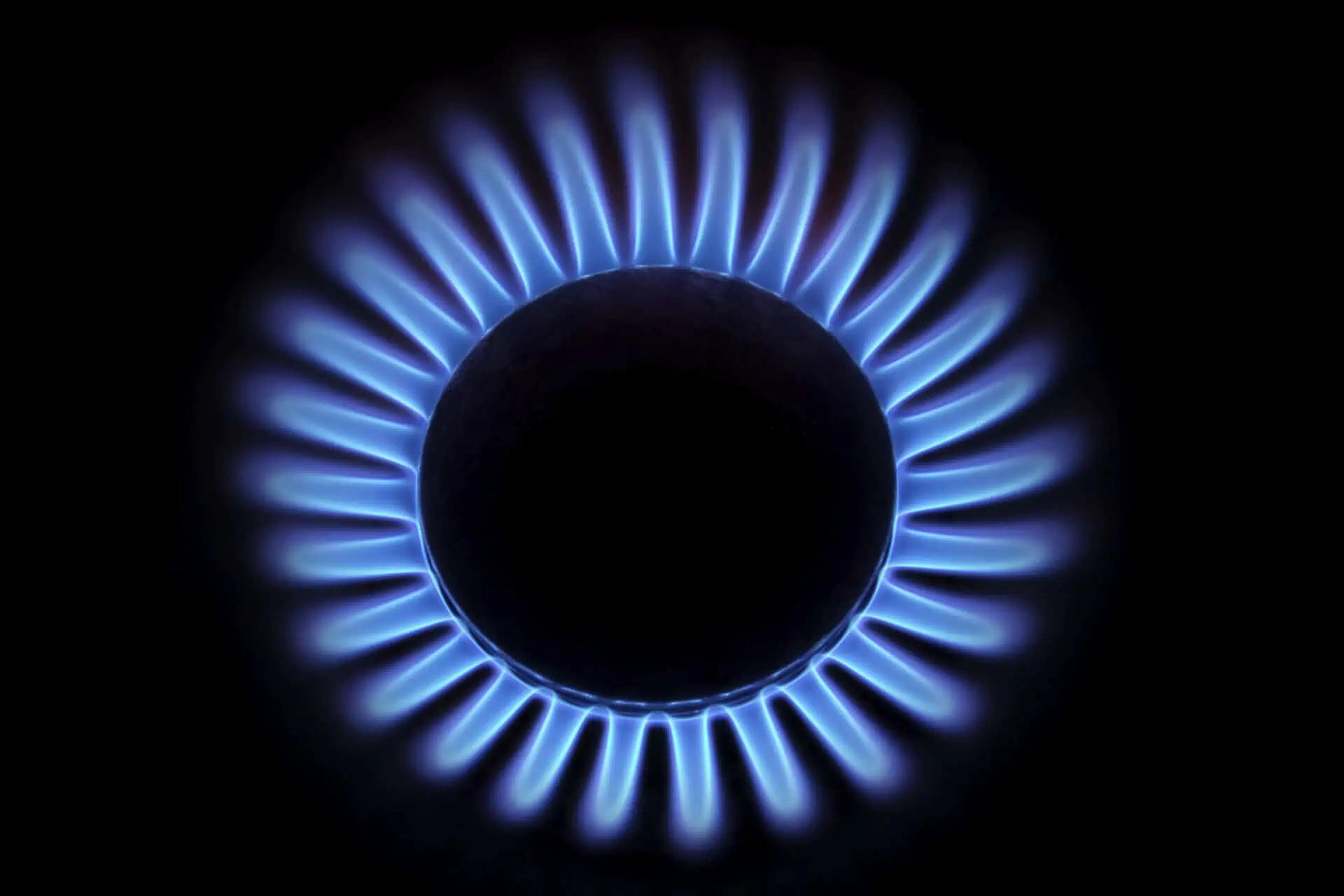 Flame from a gas cooking ring glowing in the darkness, seen from above.