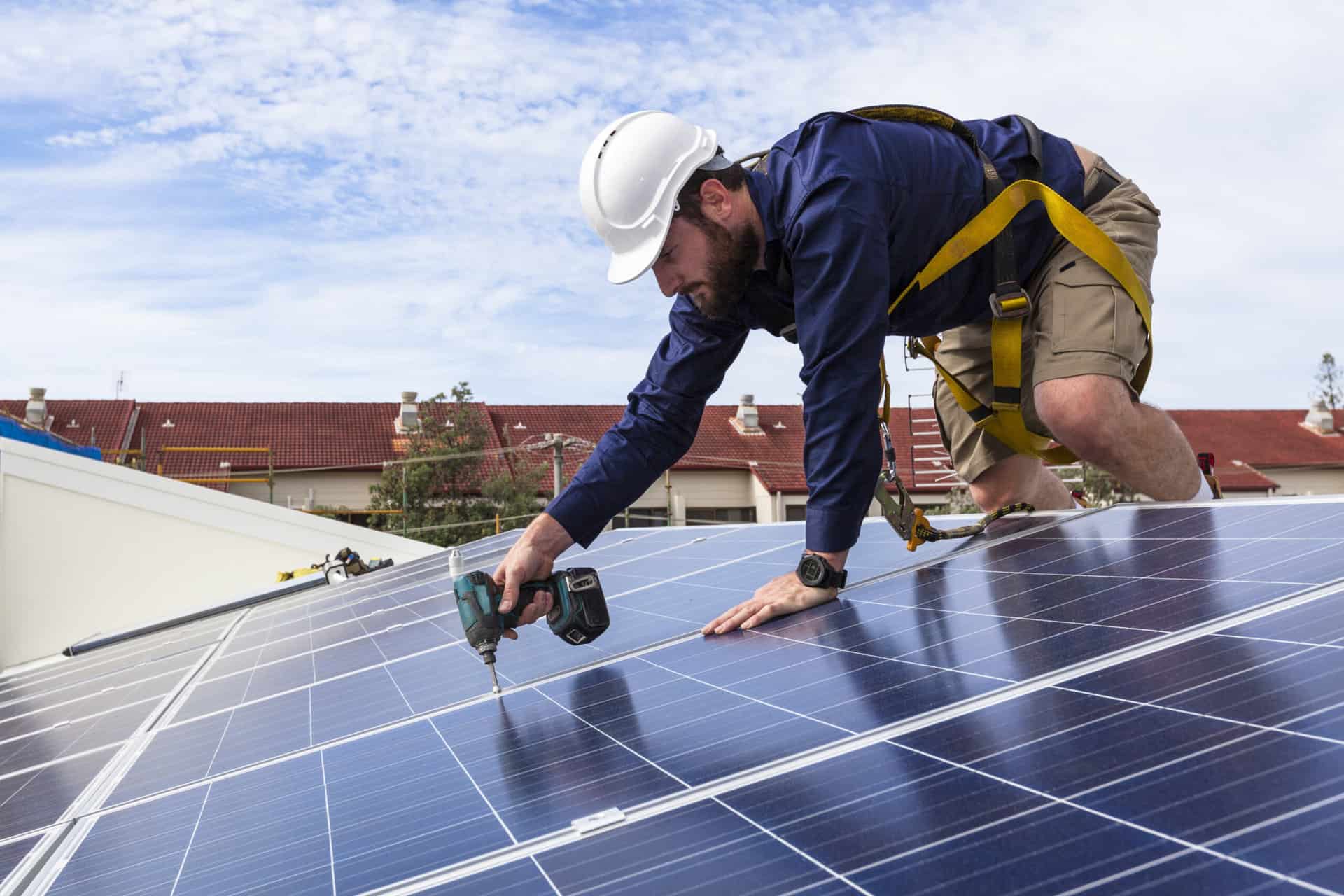A workman installs a solar PV system to the roof of a house