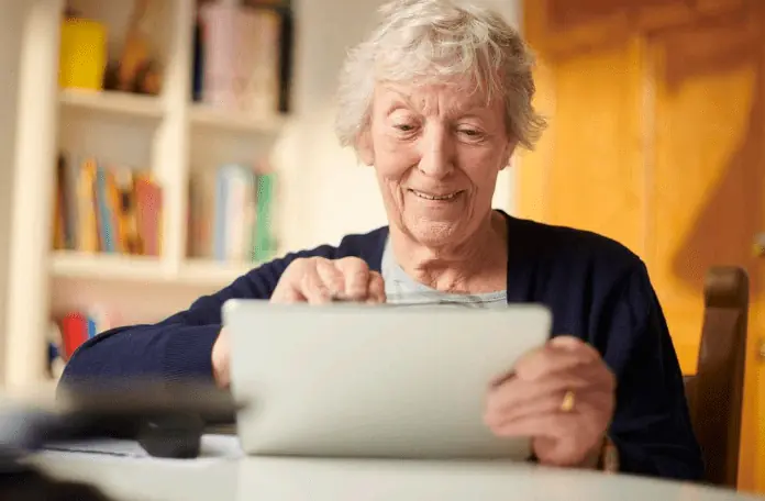 An elderly woman using a tablet to manage her energy bills