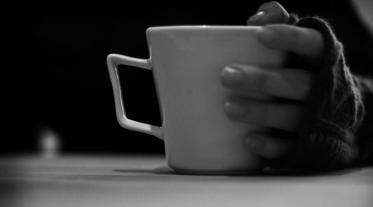 A gloved hand holding a mug of tea