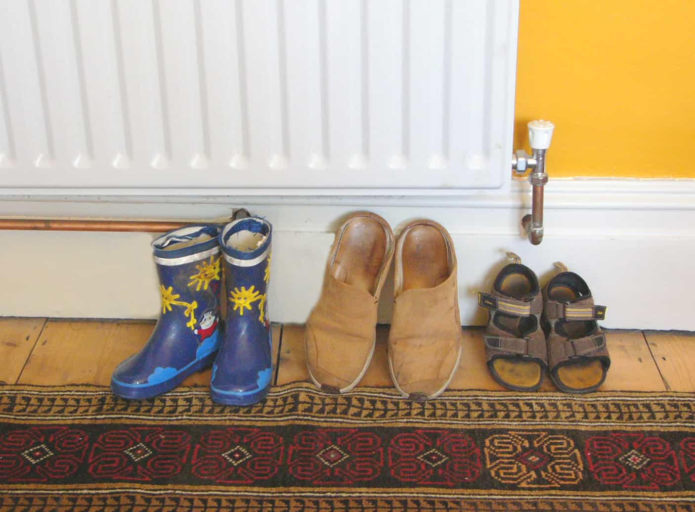A family's shoes lined up by a radiator