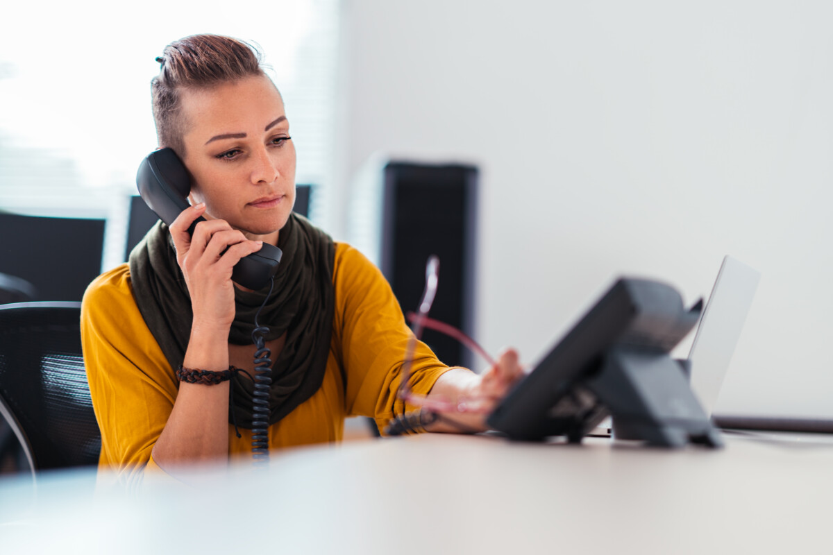 A woman in a modern office waiting on the telephone