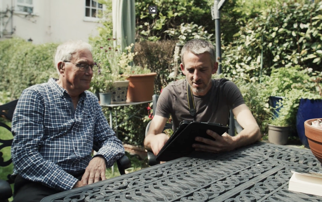 David sits in his garden with Steve from the Centre for Sustainable energy. They are looking at the results of the energy efficiency tests on his home.