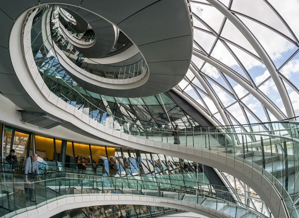 The inside of a glass-walled building, looking up at a spiral staircase.