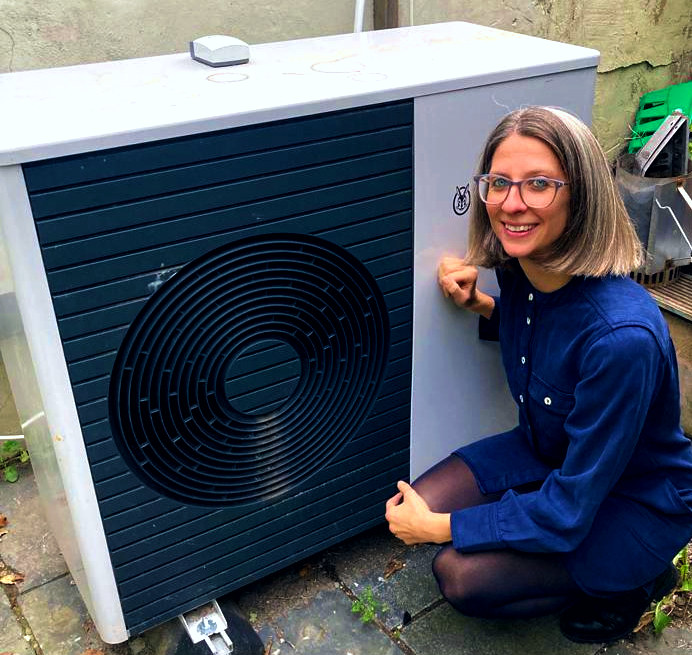 A woman crouched next to a heat pump