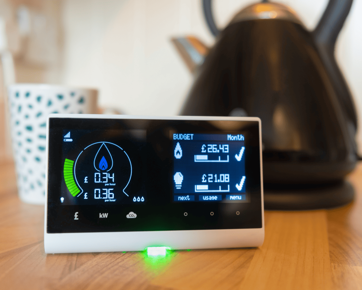 Photograph of a smart meter in home display on a countertop. A mug and kettle are blurred in the background.