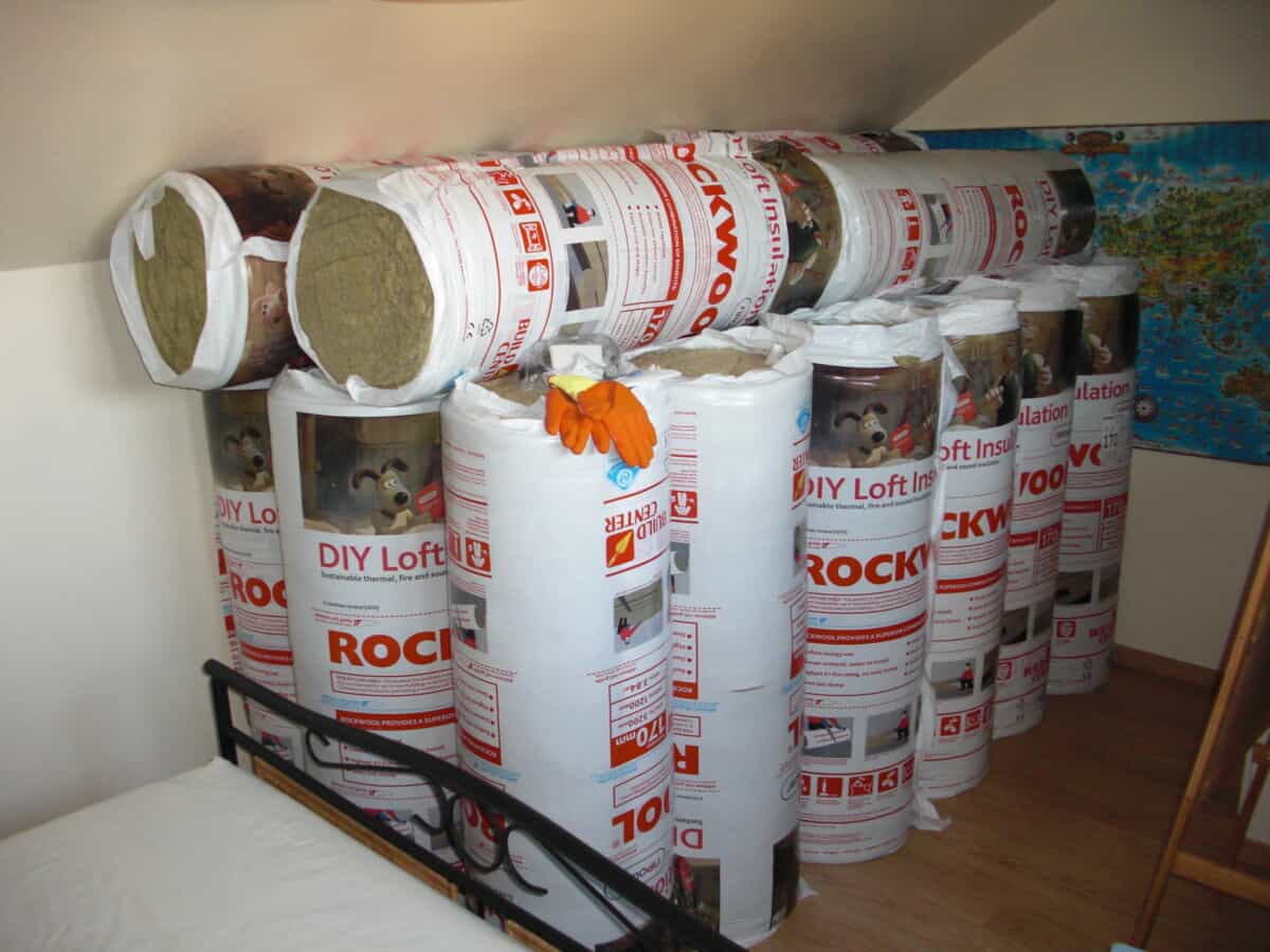 A pile of around a dozen rolls of loft insulation waiting to be laid.