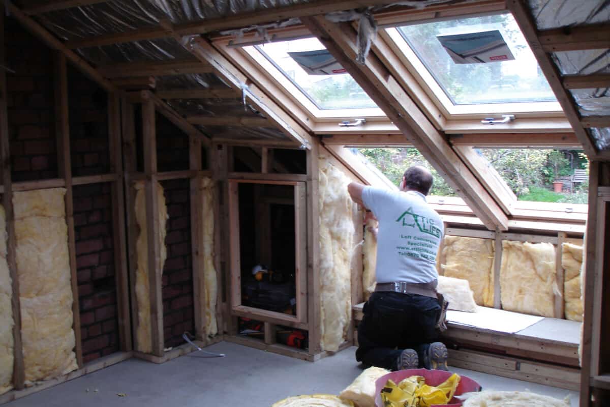 A builder fits insulation to the wall of a loft conversion.