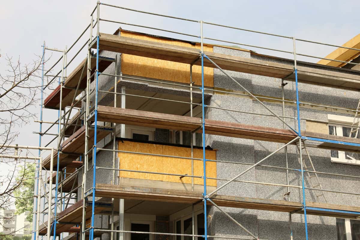 Scaffolding surrounds a low-rise block of residential apartments to which external wall insulation is being applied.