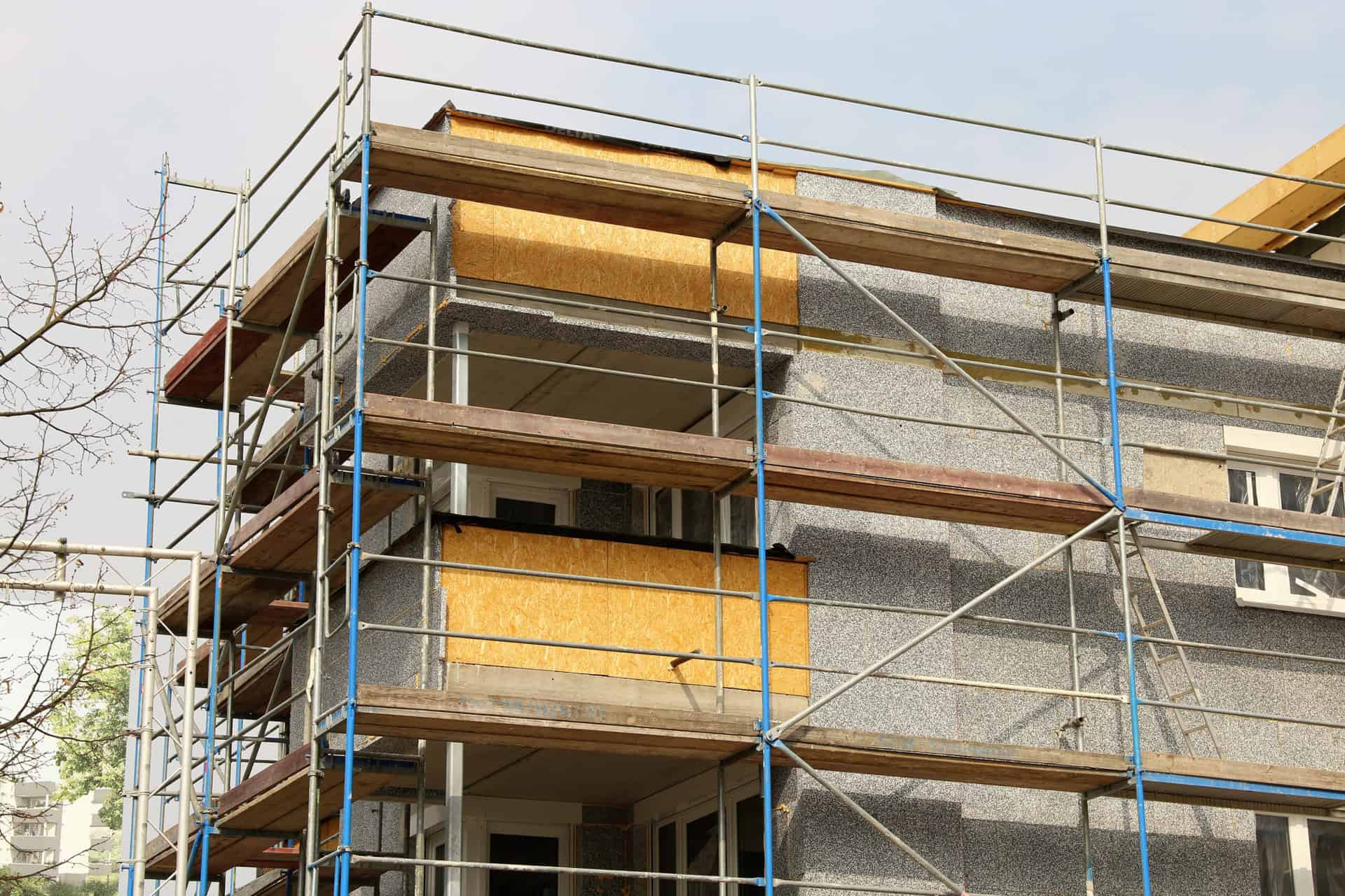 Scaffolding surrounds a low-rise block of residential apartments to which external wall insulation is being applied.