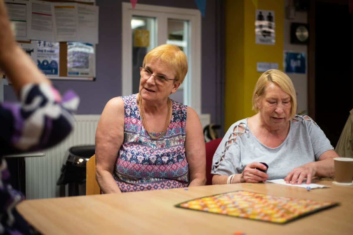 Two women sit at a table smiling.