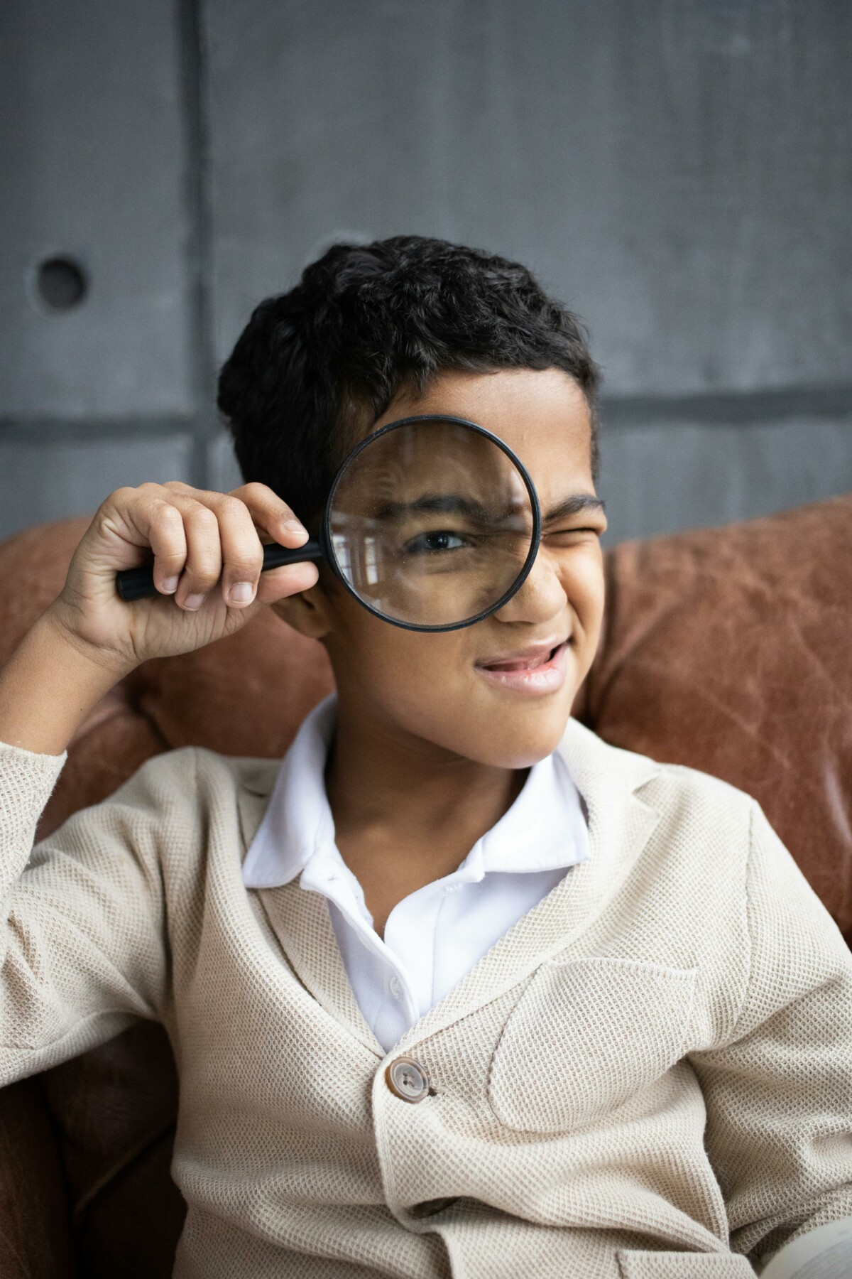 Portrait of a child holding a magnifying glass to their eye.
