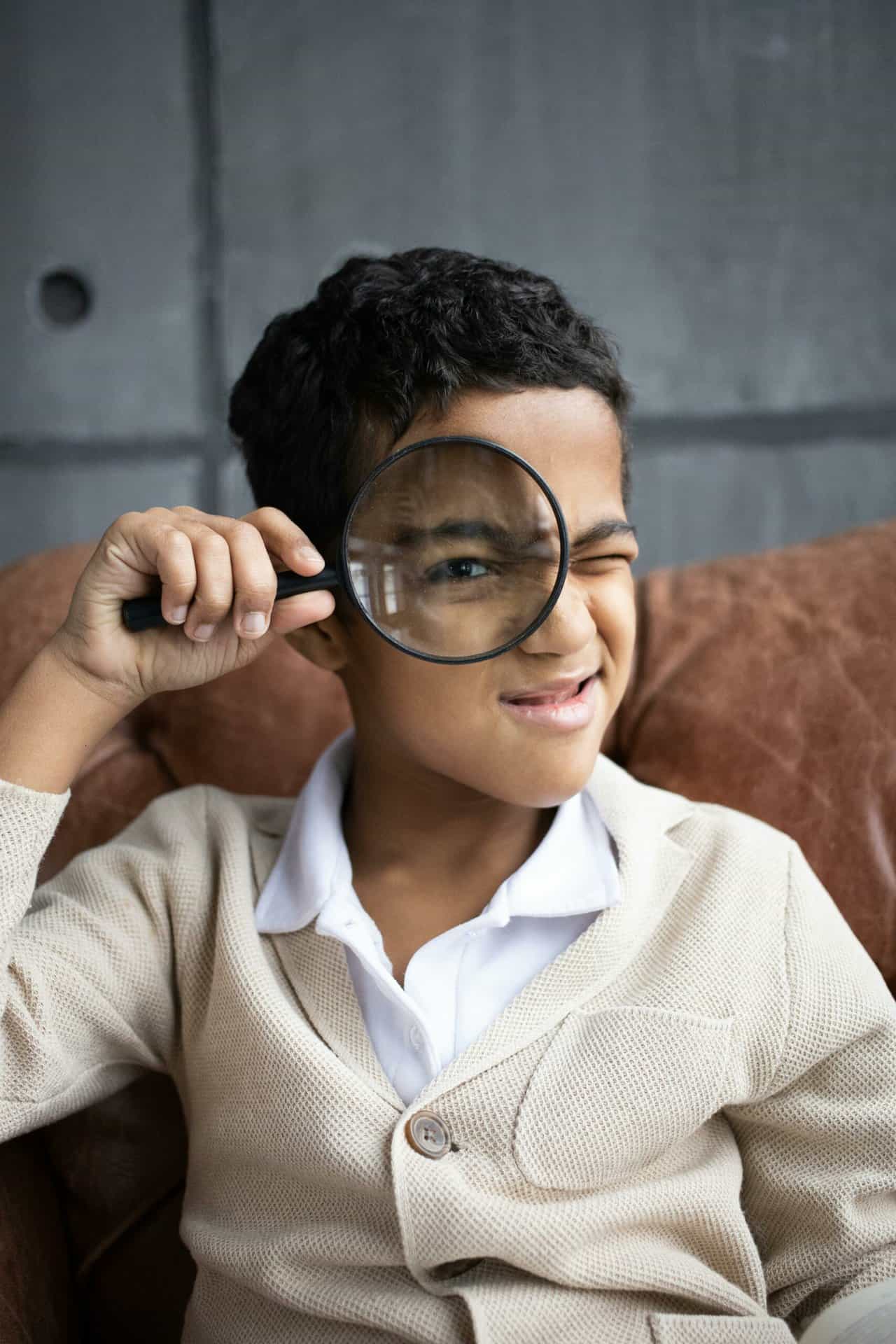 Portrait of a child holding a magnifying glass to their eye.