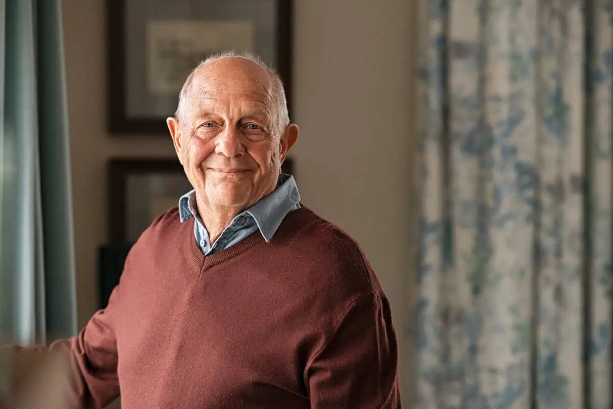 Happy senior man looking at camera at home