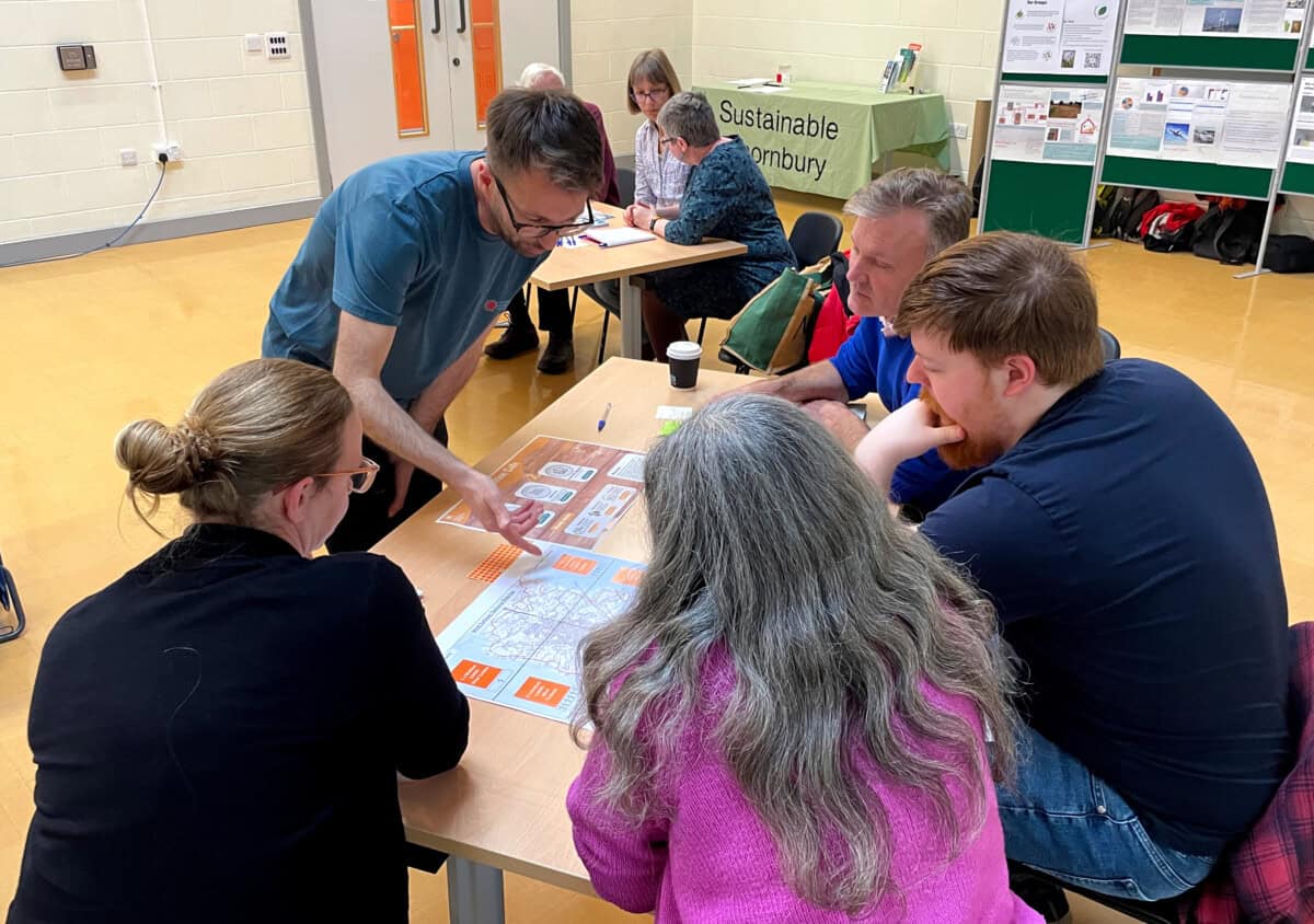 A group of five people sit around a table looking at a map as part of an energy planning workshop.