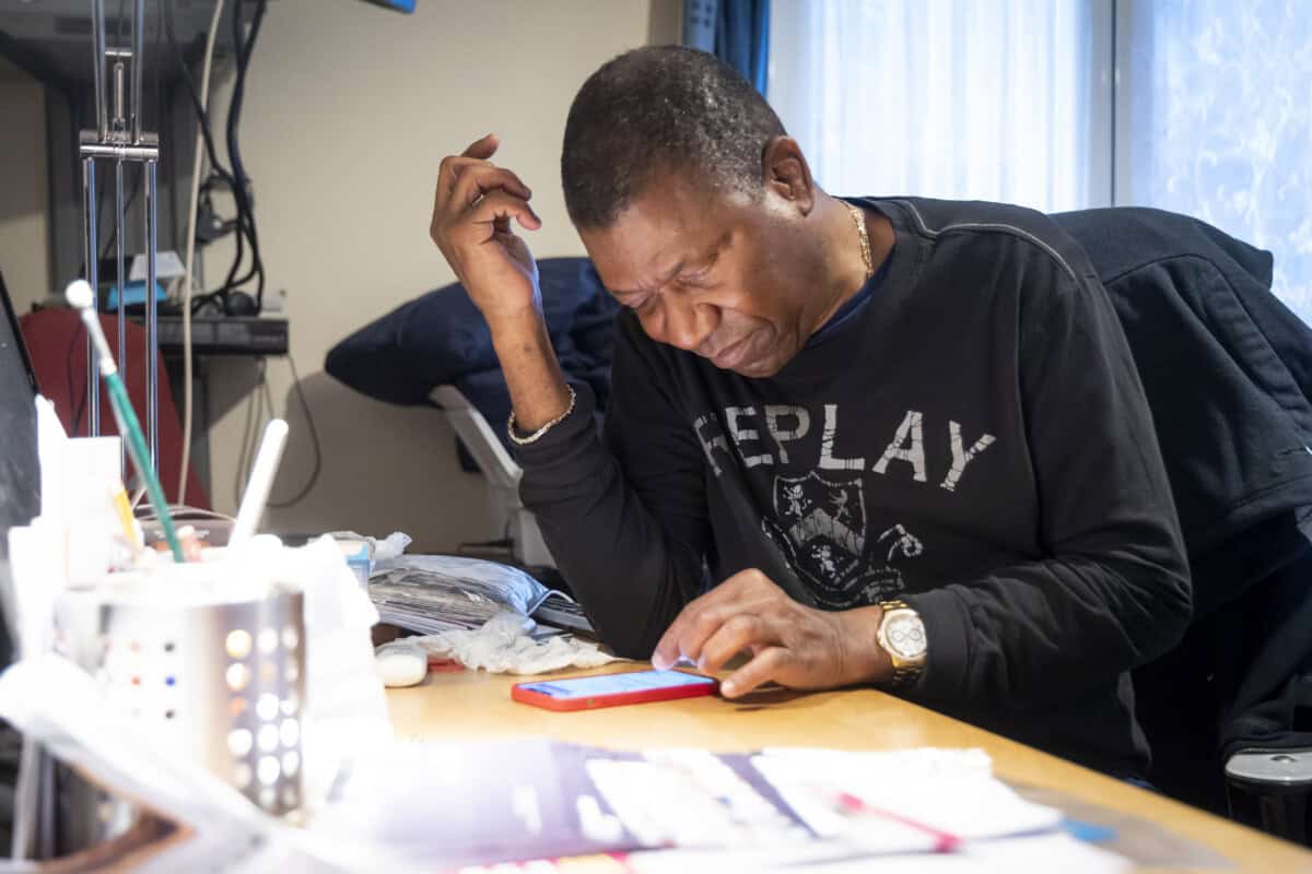 A man sits at a desk looking at a smartphone.
