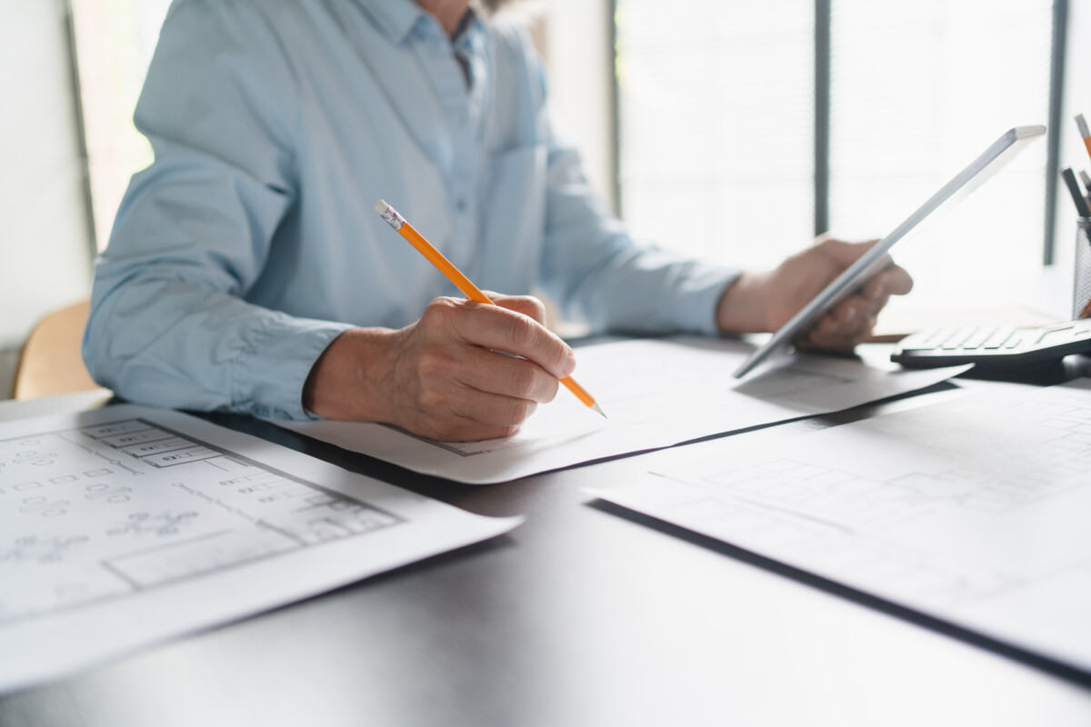 Close up of female Architect hands mature Caucasian business woman working with blueprints for architectural plan, engineer sketching a construction project, green energy concept
