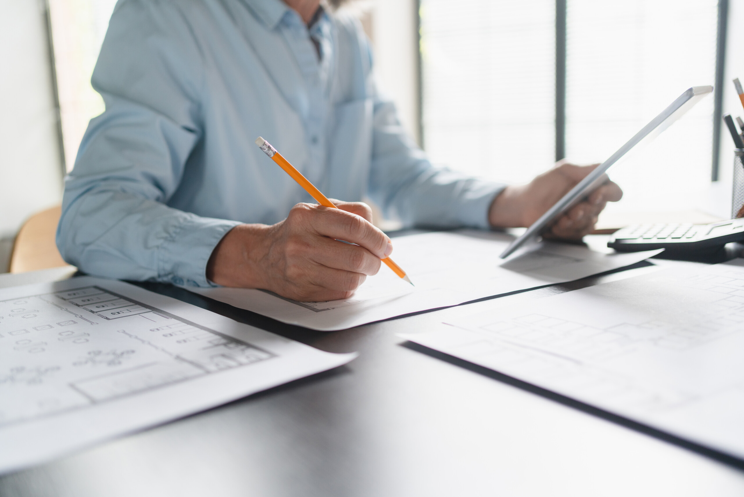 Close up of female Architect hands mature Caucasian business woman working with blueprints for architectural plan, engineer sketching a construction project, green energy concept