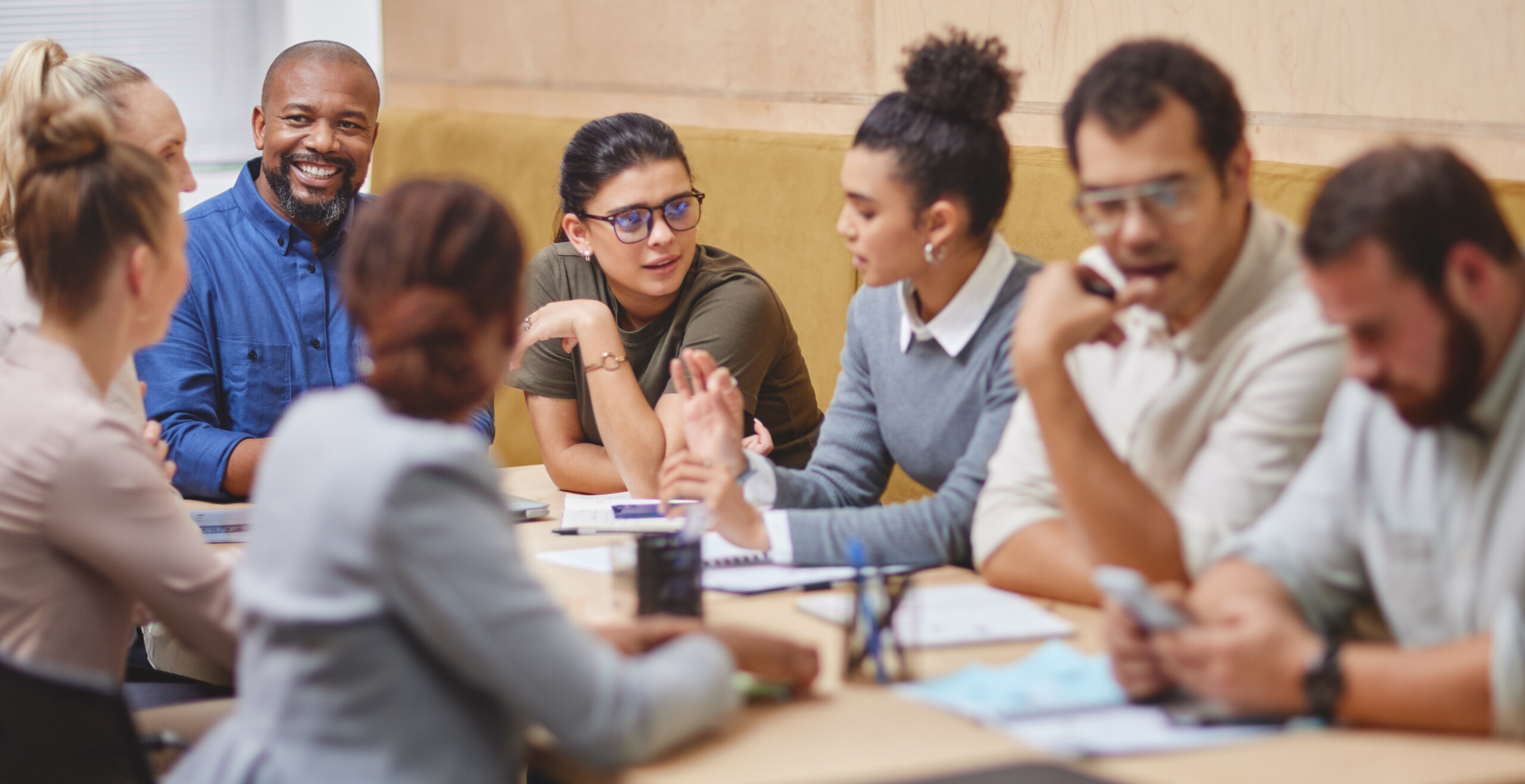 A group of people involved in a discussion, sitting around a boardroom table.