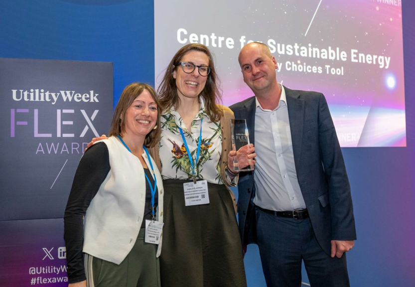 Two women on a stage smiling and receiving an award from the presenter.