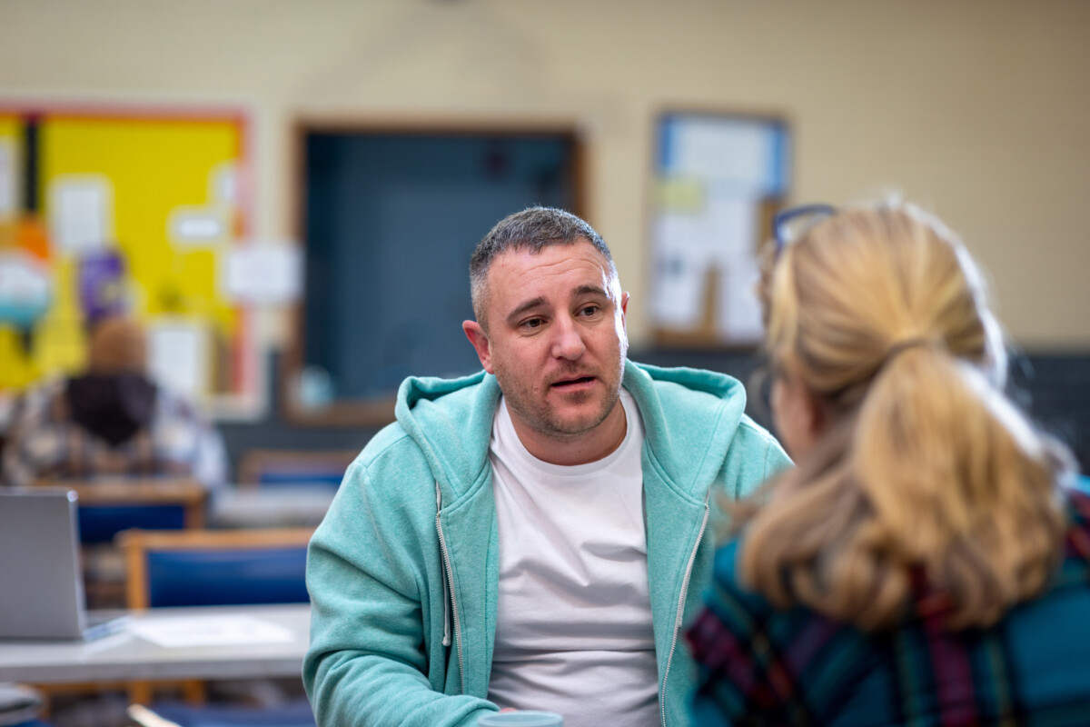 Two people having a supportive conversation in a community centre.